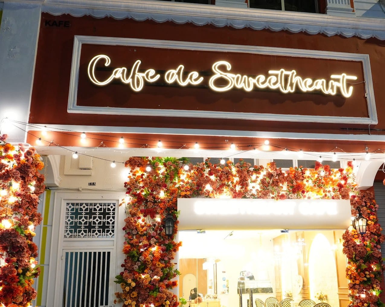 Sweetheart Cafe's shopfront, with its sign above a doorway framed in flowers and fairy lights